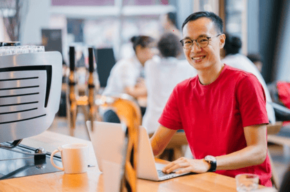 A happy customer sitting on a desk with a laptop